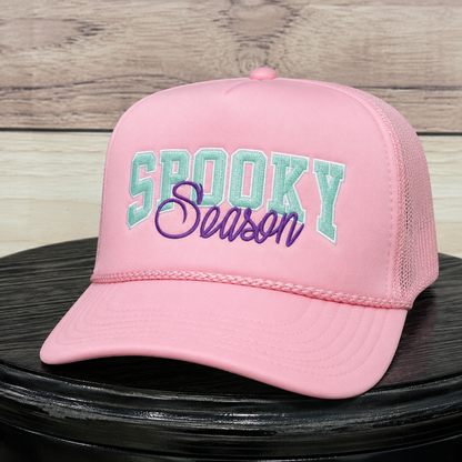 Light pink foam trucker hat with mint green chenille "Spooky" lettering and purple embroidered "Season" script, pink rope detail, and mesh back. Perfect Halloween trucker hat for women.