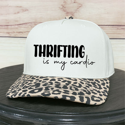 Natural cap with leopard print brim and 'Thrifting is my cardio' text on a wooden surface